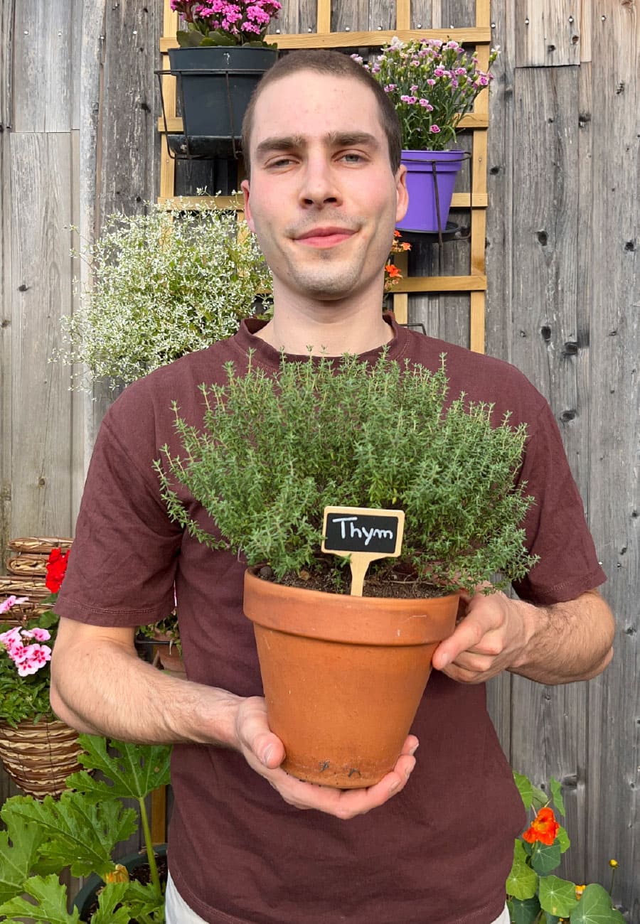 jardin-thym-evolvive Olivier, créateur du compte evolvive, sur sa terasse avec un pot de thym dans les mains